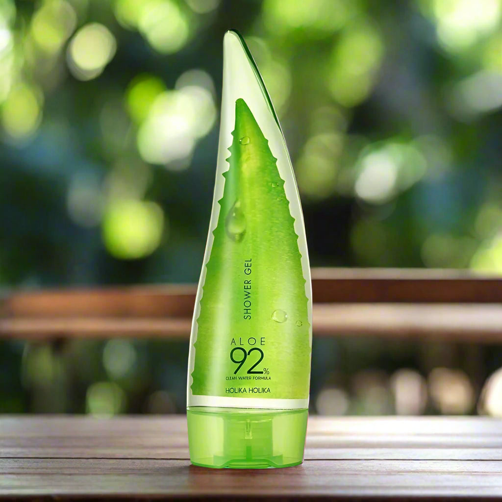 Green aloe vera shower gel bottle on a wooden surface with a blurred green background