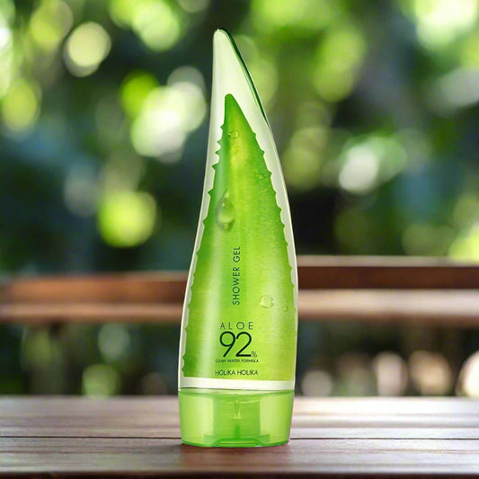Green aloe vera shower gel bottle on a wooden surface with a blurred green background