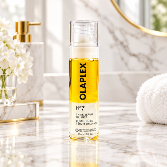 Olaplex 07 Shine Serum Oil Mist bottle next to its gold-colored packaging box on a light textured surface.