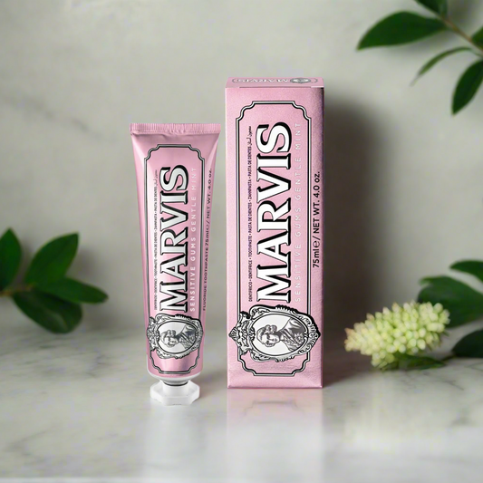 Pink Marvis toothpaste tube and packaging on a light background with greenery.